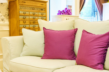 Beautiful modern living room with purple pillows on cozy sofa, interior design