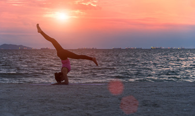 Silhouette young woman lifestyle exercising vital meditate and practicing yoga on the beach at sunset.  Healthy Concept..