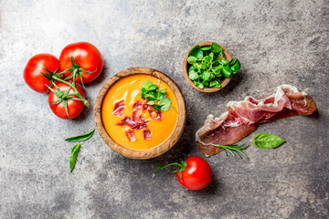 Spanish tomato soup Salmorejo served in olive wooden bowl with ham jamon serrano on stone background. Top view