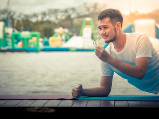 A asian young man in casual dress is in the romantic moment with flower while relaxing at the park