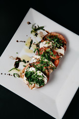 Caprese Salad on a white plate with dark background