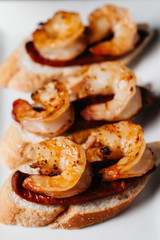 Plate of delicious  bruschetta with grilled shrimp and sausage on dark background