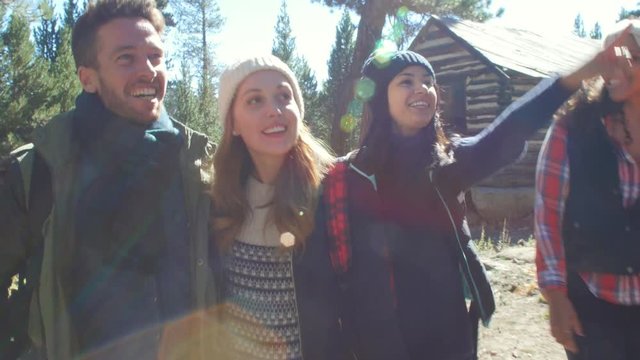Excited friends hiking past a cabin in a forest, close up, shot on R3D