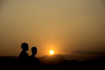 Silhouette two tourist man standing to watch over valley to sunset, Emotional scene