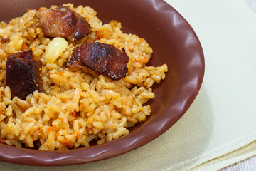 Rice pilaf with meat and vegetables on clay plate