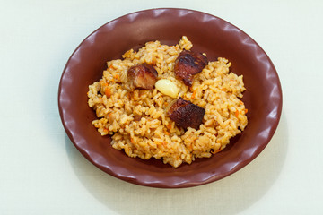 Rice pilaf with meat and vegetables on clay plate