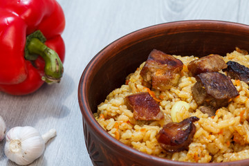 Rice pilaf in clay bowl with meat and vegetables