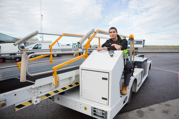 Confident Worker Sitting On Luggage Conveyor Truck