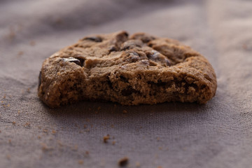 Closeup chocolate chips cookies with bite on brown background
