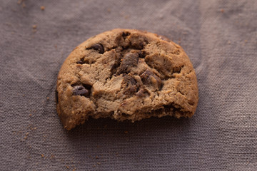 Closeup chocolate chips cookies with bite on brown background