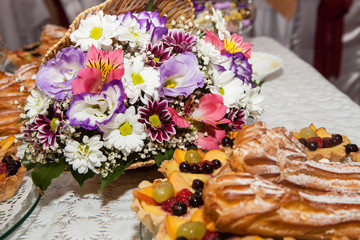 Obraz na płótnie Canvas Frozen eclair with candied fruits on a background of a colorful bouquet