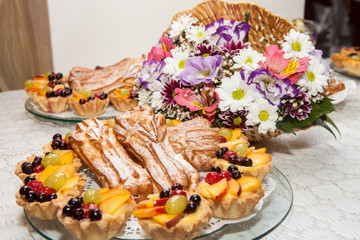 Frozen eclair with candied fruits on a background of a colorful bouquet