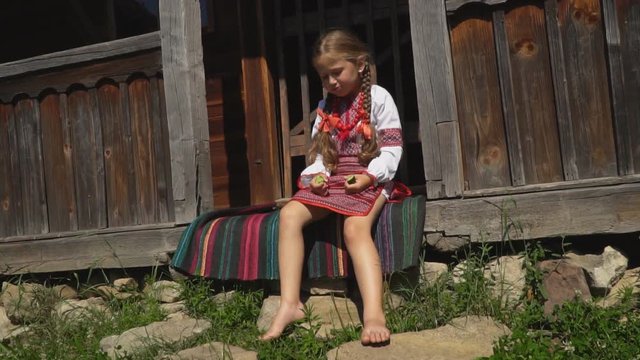 little girl is sitting on the porch of the house