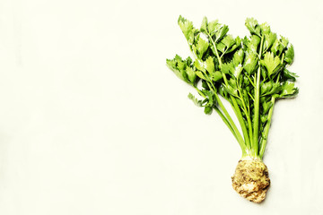 Raw root celery with green stems, gray stone background, top view