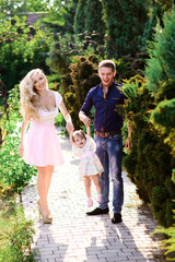 Fototapeta premium Mom, dad and little daughter walk in the Park. Happy family.