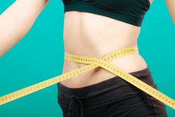 Fitness girl measuring her waistline