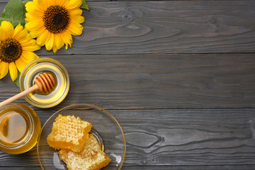 Sunflower with honey, Honeycomb and honey dipper on dark wooden table. Top view with copy space