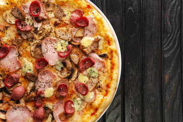 Top view of tasty pizza on dark wooden background