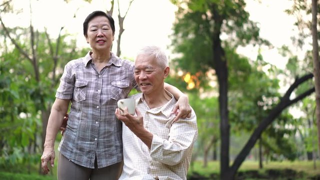 Happy Old Asian senior couple dating at park in the morning. Coffee conversation