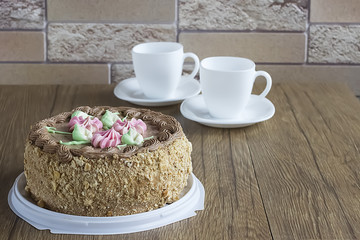 Nut cake with cream  flowers and leafs and chocolate cream  as decoration and two white cups