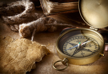antique compass with rope and book on vintage paper background