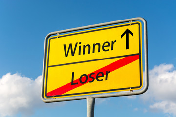 Yellow street sign with winner ahead leaving loser behind