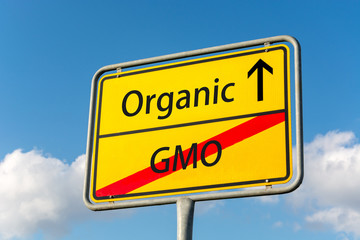 Obraz premium Yellow street sign with Organic ahead leaving GMO behind close up behind