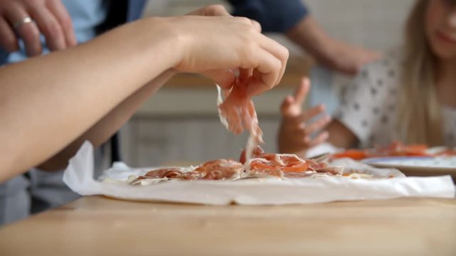 Close Up Of Children At Home In Kitchen Making Pizzas 