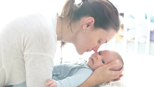 Happy mother, talking to her newborn son, stroking and kissing him