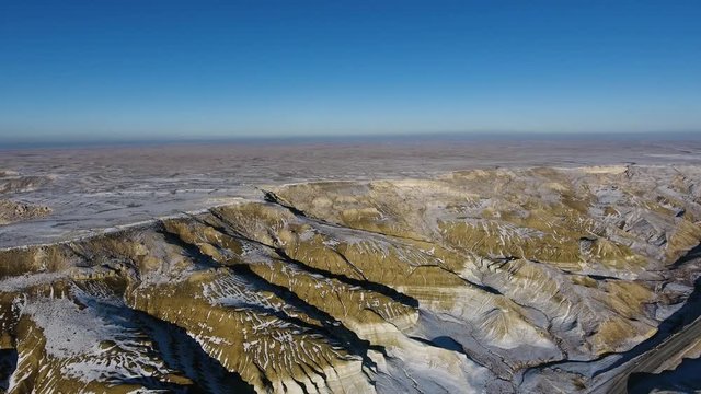 Amazing aerial view of snow-covering sandy mountains in Western Kazakhstan, Mangyshlak Peninsula. Desert in the snow.