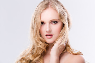 Portrait einer hübschen jungen Frau mit langen blonden Haaren vor weissem Hintergrund