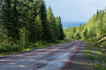 Dirt road in the forest in diminishing perspective, with a curve in some distance. Sweden, Dalarna region.