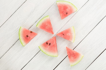 Scattered slices of fresh ripe watermelon on old wooden rustic white table