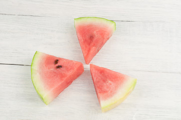 Three slices of fresh ripe watermelon on old wooden rustic white table