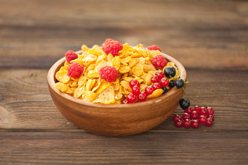 Breakfast of cornflakes with berries in wooden bowl