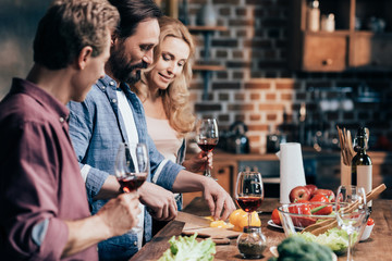 friends drinking wine while cooking dinner