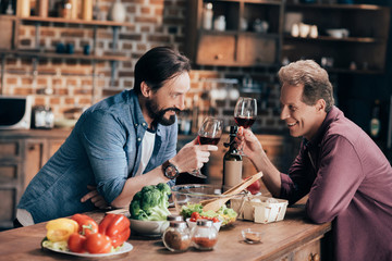men drinking wine in kitchen