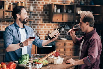 men drinking wine in kitchen