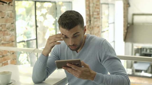 Man looks shocked while browsing internet on smartphone, steadycam shot
