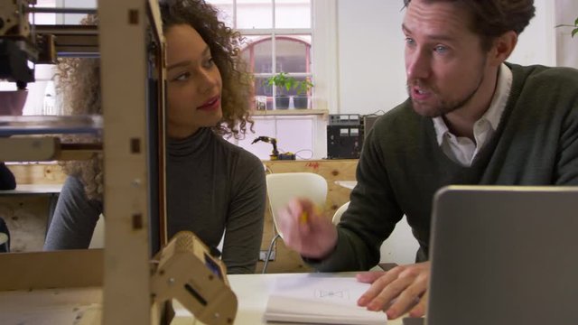Two designers working in a design studio watch a 3D printer, shot on R3D
