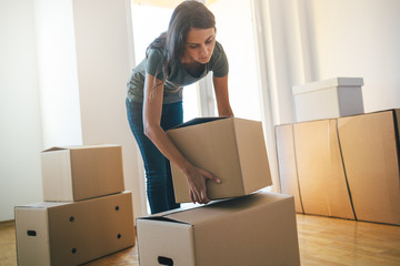 Young woman dropping cardboard box. Moving into new home