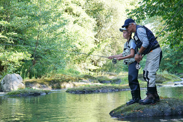 Dad with young boy fly-fishing in river