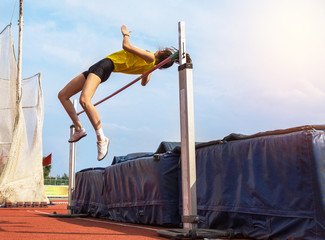 female athlete in action high jump over bar in track and field - 172956259