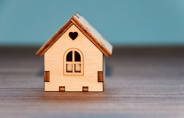 Miniature wooden toy house on a wooden table with a colored background