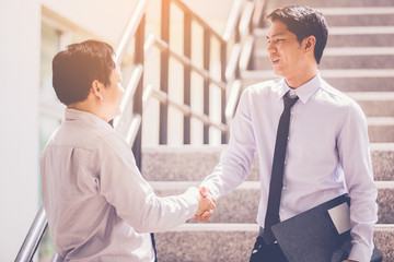 Businessman with stylus pen touching the screen of smart phone and discuss with business partner