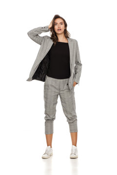 astonished young beautiful woman in a jacket, blouse, sneakers and trousers