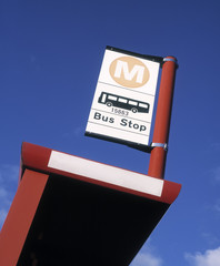 Close up of bus stop and sign against blue sky