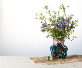 Grassland flowers in vase on white wooden table