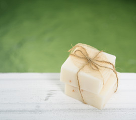 Fototapeta na wymiar Spa milk soap on white wood table with green pond background