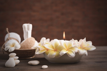 Fototapeta na wymiar Spa wellness and treatment with essential oils,zen stone,towels,candle,hearbal massage ball and frangipani flowers on wooden table with brick wall background